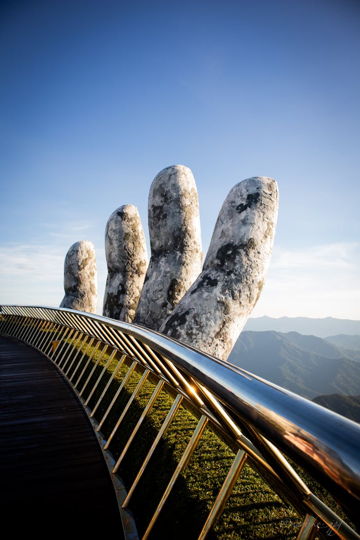The iconic Golden Bridge held by giant stone hands at Ba Na Hills Da Nang, featuring stunning mountain views and French Village architecture